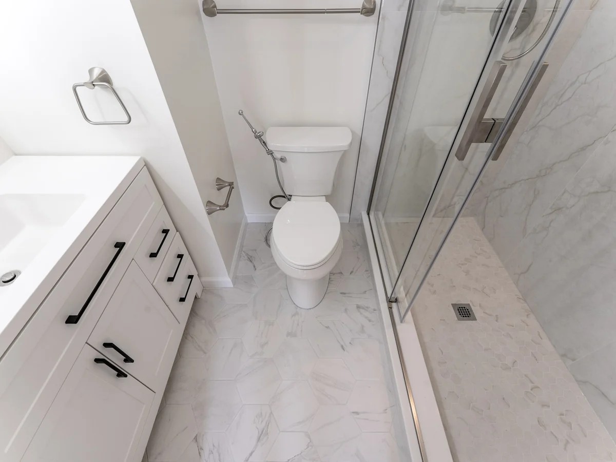 Renovated bathroom in Springfield, VA with a walk-in shower, marble-look tile, glass enclosure, and modern vanity.